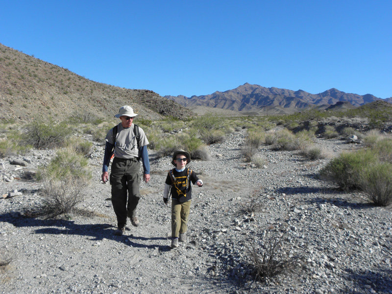 06-Poppy_and_Kenny_walking_down_wash-no_trail-Hwy_93_distance