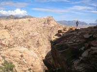 26-Eric_on_cliff_edge_pointing_to_our_destination_behind_me